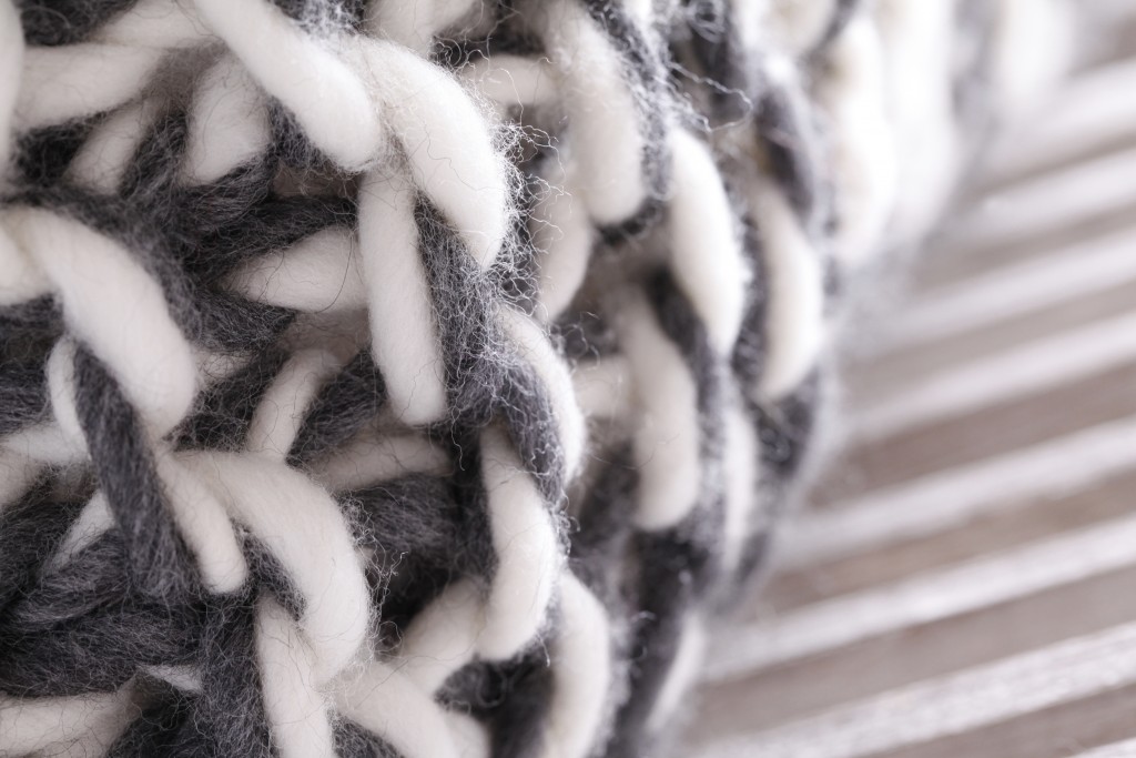 Détail du coussin "VERTIGE" : mélange de laines Mérinos tricotées à la main en mailles géantes