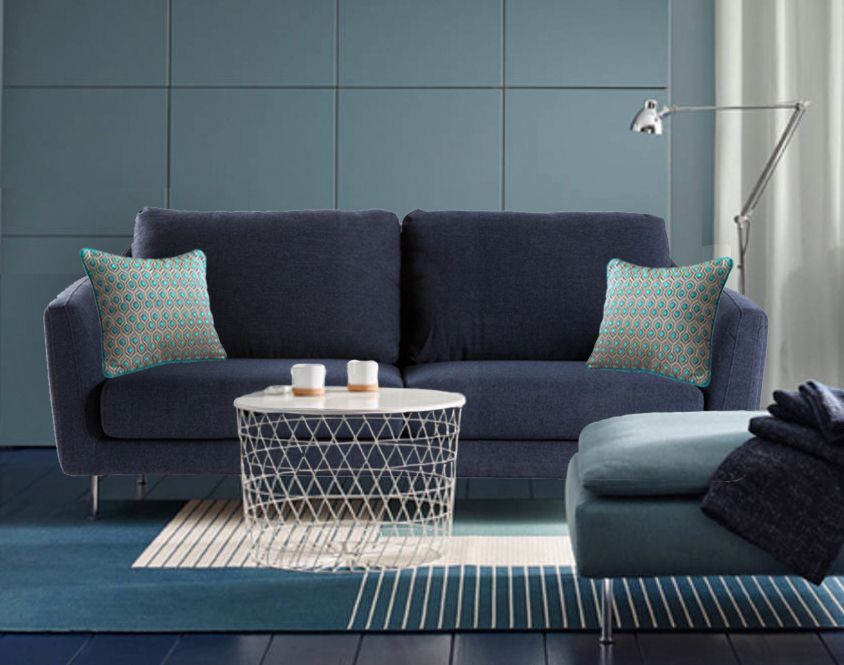 Un exemplaire de notre coussin en velours à motifs gris et turquoise MARQUISES disposé à chaque extrémité de ce canapé bleu indigo