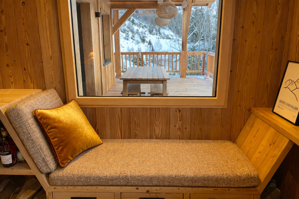 Coin détente en bois avec coussins sur mesure Maison du Coussin dans un chalet contemporain des Alpes