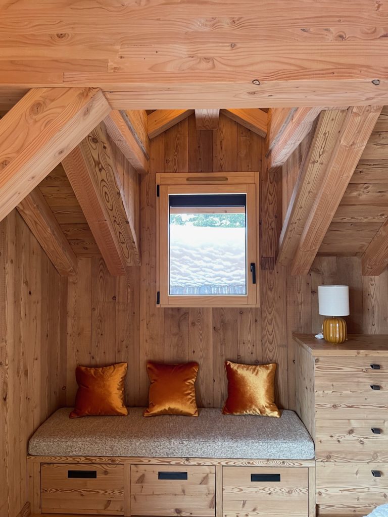 Banquette de chambre en bois avec coussin d’assise sur mesure et coussins décoratifs en velours satiné ARIZONA dans un chalet alpin